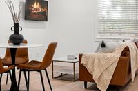 Elegant and modern open-concept living space with rich brown leather furnishings, sleek kitchen with stainless steel appliances, and cozy dining area, perfect for contemporary lifestyles.