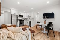 Chic open living space with a cozy seating area, modern kitchen, and stylish dining set, perfect for comfortable city living.