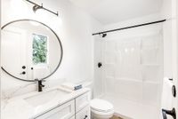 Bright and modern bathroom boasting a sleek marble vanity, circular mirror, and elegant shower.