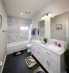 Elegant bathroom featuring double vanity with marble countertops, sleek tile flooring, and shower-tub combo accented by stylish decor.
