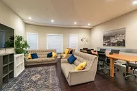 Elegant and cozy living room with plush sofas and vibrant cushions, complemented by a spacious dining area with sleek chairs and a wooden table.