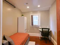 Cozy bedroom with modern decor, featuring a comfortable bed, sleek wardrobe, and a functional workspace by the window.