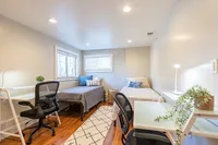 Bright and inviting bedroom with two beds, elegant workspaces, and natural light enhancing the modern decor.