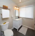 Elegant bathroom design featuring a modern vanity with marble countertop, large window with blinds, and sleek tile flooring for a luxurious touch.