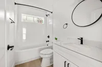 Elegant bathroom with a sleek white design, featuring a modern vanity, round mirror, and a spacious bathtub.