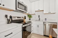 Elegant kitchen with sleek stainless steel appliances, modern white cabinetry, and polished countertops.