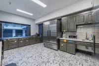 Modern kitchen with sleek gray cabinets, large stainless steel refrigerator, and patterned tile flooring.