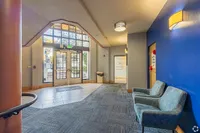 Inviting apartment lobby with modern seating, vibrant blue accent wall, and elegant natural lighting through large glass doors.