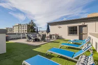 Chic rooftop terrace featuring modern lounge chairs, a cozy seating area, and stunning views of the city skyline.