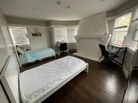Bright and roomy bedroom with elegant white brick fireplace, two cozy beds, and large windows offering serene views.