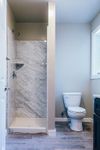Elegant bathroom featuring a modern marble shower and sleek porcelain toilet, full of natural light.