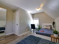 Cozy and bright attic bedroom with modern decor, featuring a comfortable bed, stylish chair, and a small desk by the window, perfect for relaxation or study.
