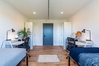 Bright and modern shared bedroom featuring sleek desks, stylish chairs, and abundant natural light, perfect for a productive and comfortable living environment.