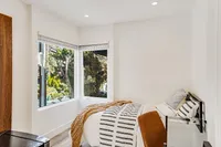 Cozy bedroom with a stylish bed and large windows offering a scenic outdoor view, flooding the space with natural light.