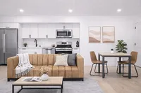 Modern open-concept living space with sleek kitchen, cozy tan sofa, and chic dining area, perfect for stylish urban living.