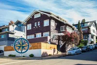 Charming multi-story apartment building with classic architecture, nestled in a picturesque neighborhood with tree-lined streets and ample parking.