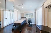 Bright and airy bedroom with a modern single bed, sleek desk, and hardwood floors, ideal for maximizing comfort and productivity.