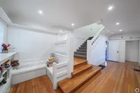 Charming and bright staircase in a modern home, featuring elegant wooden floors and built-in shelving, creating a warm and inviting entryway.