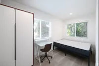 Bright and cozy bedroom with large windows, featuring a comfortable bed, sleek wardrobe, and modern study area.