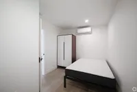 Bright and modern bedroom featuring sleek furnishings, airy white walls, and a minimalist wardrobe.