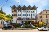 Modern apartment building with unique architectural design, featuring large windows, balconies, and lush landscaping in a vibrant neighborhood.