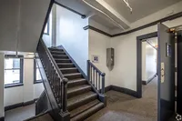 Inviting hallway in modern apartment building featuring elegant staircase with sleek railings and plush carpeting, complemented by large windows for natural light.