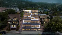 Modern apartment building with illuminated windows nestled in a lush, green neighborhood with a mix of traditional and contemporary architecture.