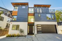 Modern three-story home with sleek architectural design, large windows, and a spacious garage set in a serene neighborhood.