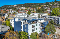 Vibrant neighborhood view with a modern apartment building, scenic hillside backdrop, and lush greenery.
