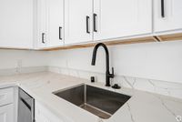 Sleek modern kitchen with elegant marble countertops, stylish black faucet, and pristine white cabinetry.