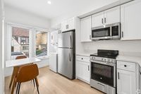 Bright modern kitchen with sleek stainless steel appliances, white cabinetry, and a cozy dining nook with natural light.