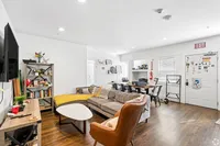 Inviting living space with stylish furnishings, cozy sectional sofa, modern armchair, and hardwood floors, ideal for vibrant gatherings or quiet relaxation.