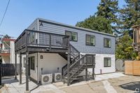 Contemporary two-story duplex with sleek gray siding and private balconies set amidst lush greenery.