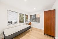 Bright and inviting bedroom with large windows, sleek wooden floors, and modern wardrobe, perfect for serene living.