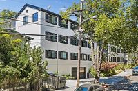 Charming multi-story apartment building with lush greenery, situated in a picturesque neighborhood with tree-lined streets.