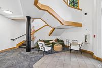 Chic apartment lobby featuring modern seating under a stylish wooden staircase, offering a welcoming and contemporary atmosphere.