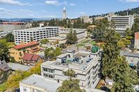 Aerial view showcasing a vibrant neighborhood with contemporary and historic architecture, lush greenery, and scenic cityscape.