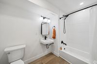 Modern bathroom design featuring sleek fixtures, a chic vanity with illuminated mirror, and a stylish shower-tub combination.