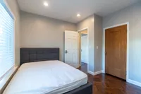 Inviting bedroom with a modern grey headboard, polished wooden floors, and soft natural light.