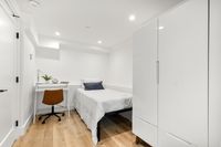 Minimalist bedroom with a cozy single bed, white wardrobe, and a sleek work desk with a brown chair.