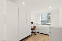 Spacious and bright modern bedroom featuring a large wardrobe, a cozy bed, and a sleek desk with a chair.