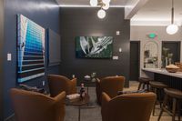 Elegant lounge area featuring cozy armchairs, modern art pieces, and a sleek bar with wooden stools.