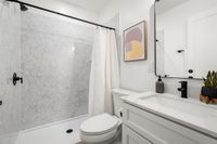 Bright, modern bathroom featuring a marble shower, white vanity with sleek fixtures, and contemporary artwork.