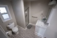 Modern bathroom with sleek tile flooring, a glass shower, and a stylish vanity, bathed in natural light.