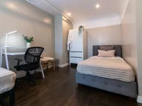 Cozy bedroom with modern decor, featuring a comfortable bed, sleek desk with chair, and elegant wardrobe, perfect for a relaxing retreat.