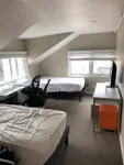 Bright and cozy bedroom with two beds, a sleek glass desk, modern office chair, and a wall-mounted TV, perfect for a comfortable and productive space.