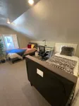 Cozy attic bedroom featuring two single beds, a study desk with chair, and a bright window with natural light.