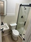 Modern bathroom featuring a sleek glass shower, compact sink, and contemporary toilet with stylish fixtures.