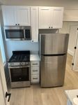 Modern kitchen featuring stainless steel appliances, sleek white cabinetry, and elegant hardwood flooring.