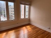 Bright corner room with beautiful hardwood floors, large windows offering stunning city views, and ample natural light.